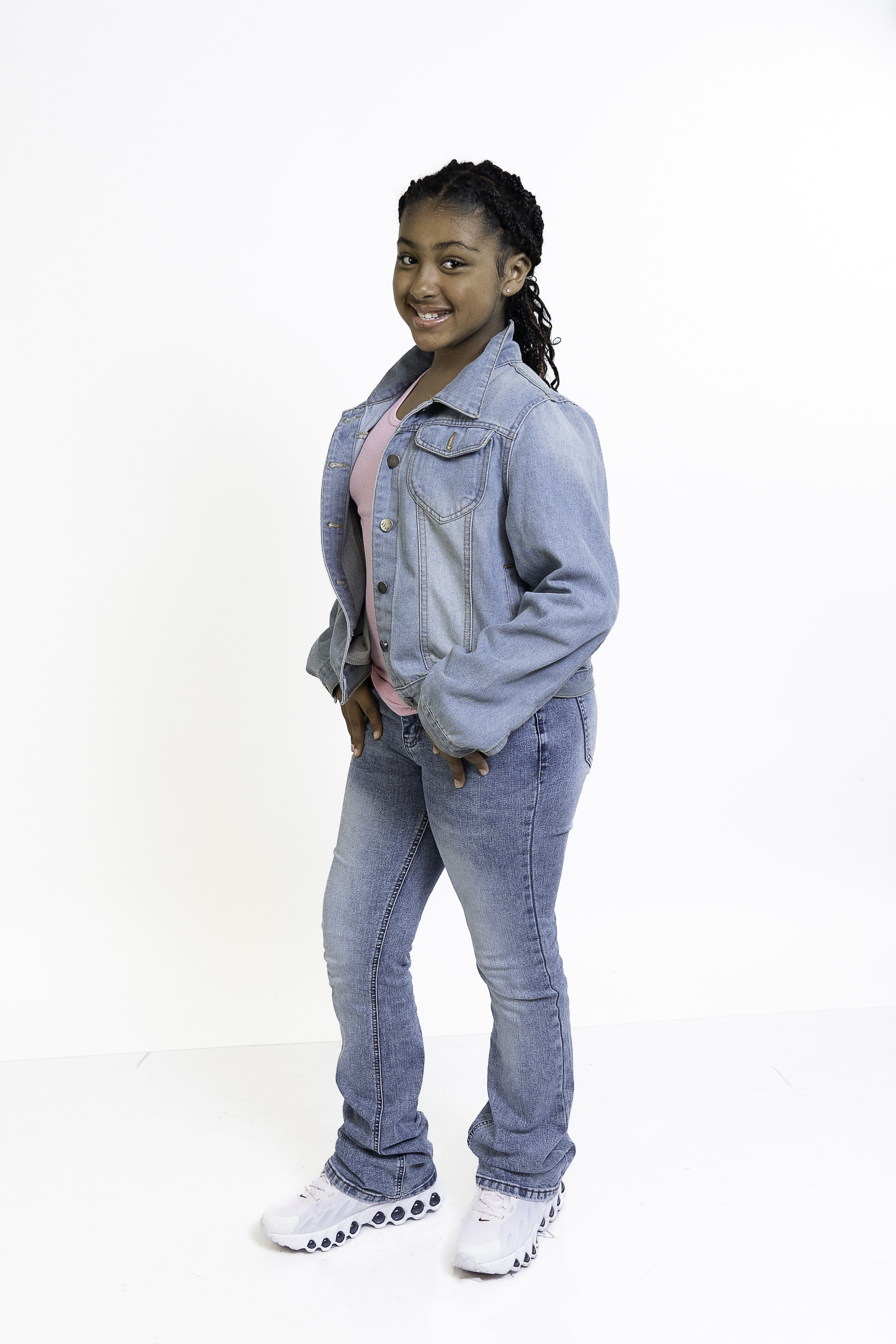 Eleaya Neveah, young actress and model, standing full-body photo in a denim jacket and jeans with a big smile